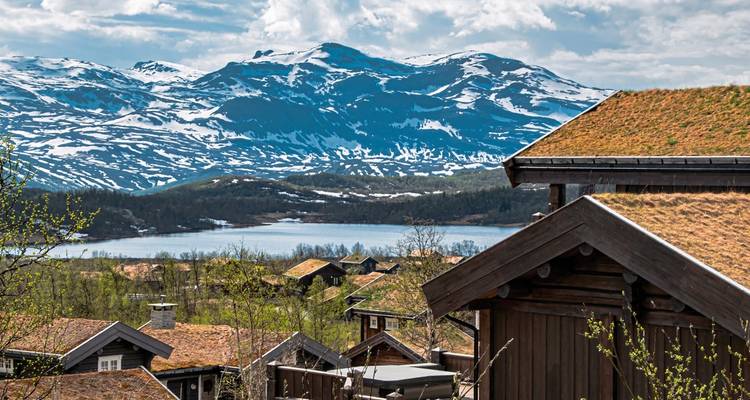 Malerische Berglandschaft mit traditionellen Häusern und einem See.