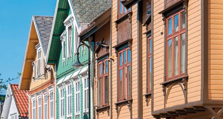 Bunte Holzhäuser mit dekorativen Details und buschigen Bäumen.