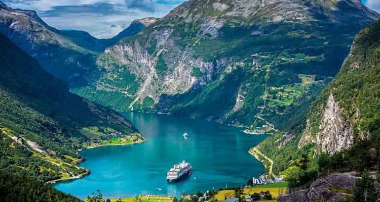 Majestätischer Blick auf einen Fjord mit einem Kreuzfahrtschiff und waldbedeckten Hängen.