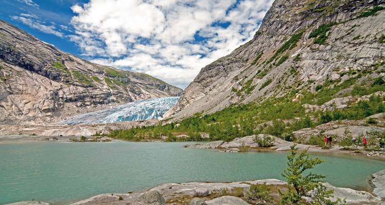 Un grand glacier niché entre des montagnes rocheuses et un lac glaciaire.