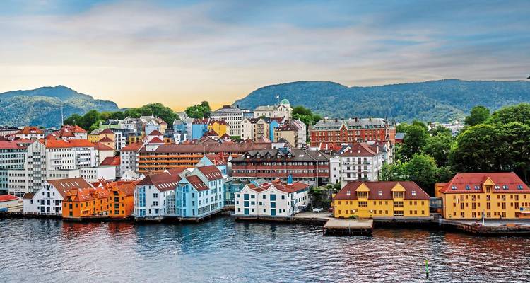 Un paysage urbain coloré au bord de l'eau contre des collines vertes et des montagnes près d'un fjord.