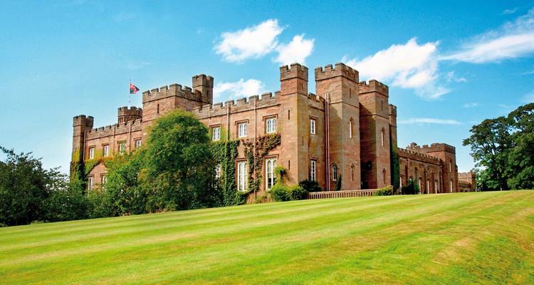 A historic castle with expansive green lawns and blue sky.