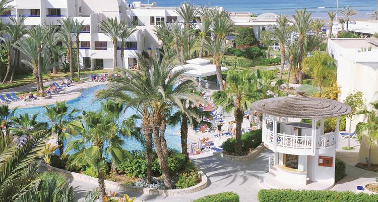 Hotelresort mit Swimmingpools und Palmen am Strand.