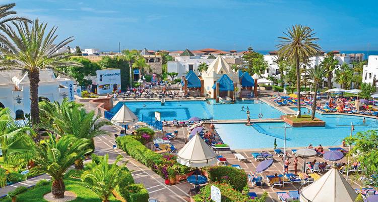 Außenansicht des Resorts mit Schwimmbädern und Palmen.