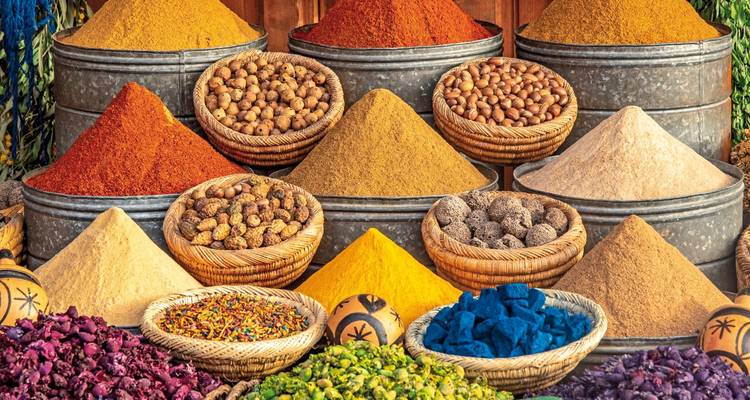 Colorful spices and herbs displayed in baskets at a market.