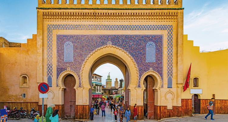 A historic gate leading into a bustling market street.