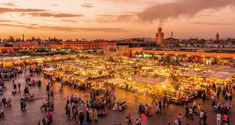 Een bruisende marktplaats met levendige kraampjes en mensen tijdens zonsondergang.