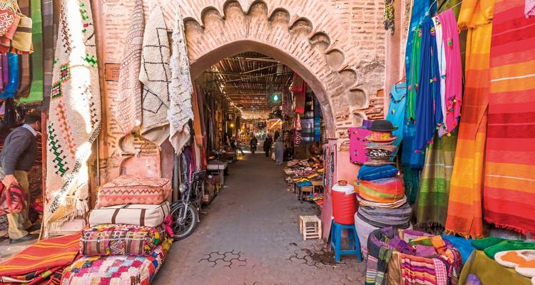 Bunte Marktstraße in Marrakesch mit Textilien und Kunsthandwerk.