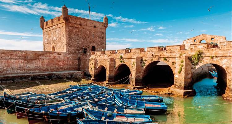 Eine Küstenfestung mit vertäuten blauen Booten in einem Hafen.