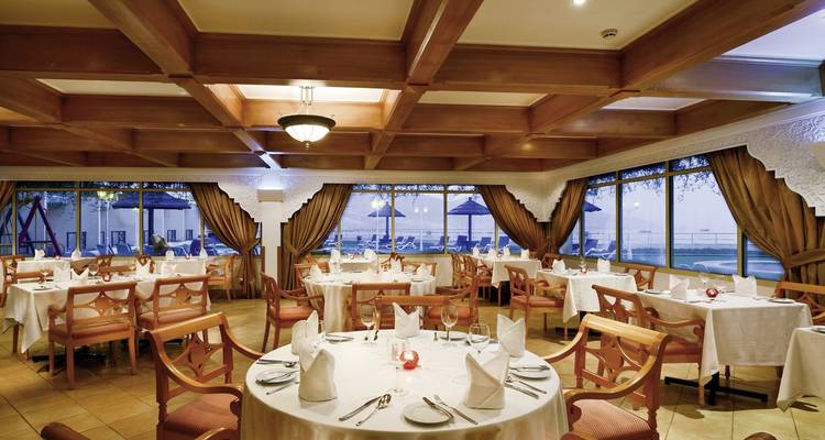 Restaurantinterieur met gedekte tafels voor het dineren bij een raam.