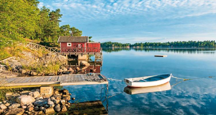 Lakeside with a small boat and red cabin.