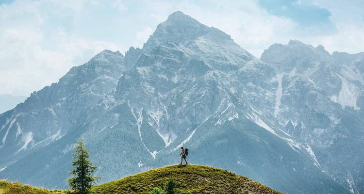 Eenzame wandelaar met een grote rugzak voor een massieve berg.