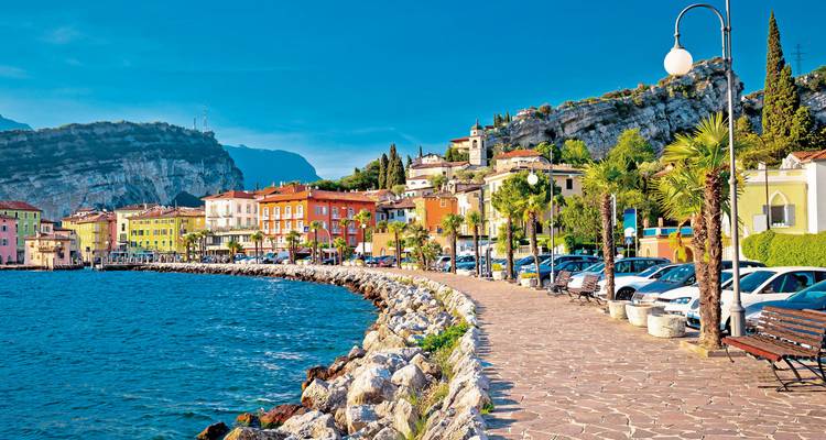 Eine Uferpromenade mit bunten Gebäuden und geparkten Autos.