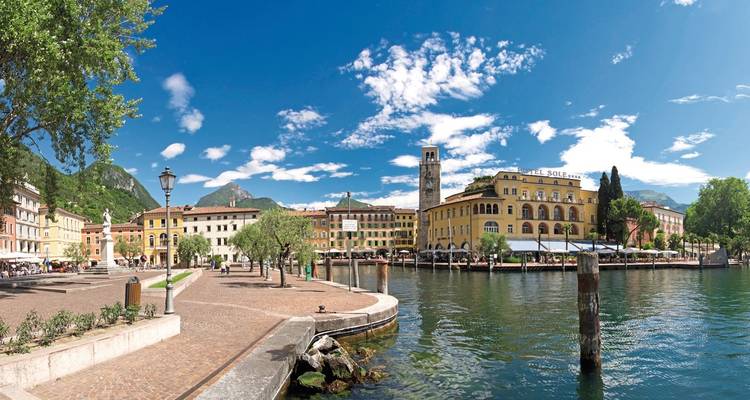 Uferpromenade mit historischen gelben Gebäuden unter blauem Himmel.