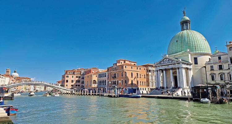 Großkanal in Venedig mit der Kuppelkirche San Simeone Piccolo, klassischen Brücken und Booten unter klarem blauen Himmel.