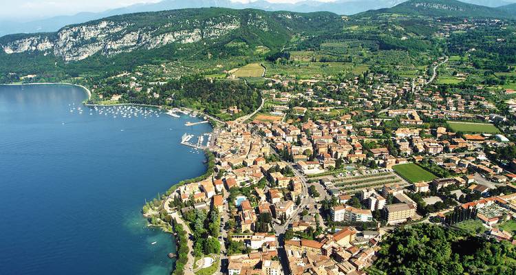 An aerial view of a city by a lake surrounded by mountains.
