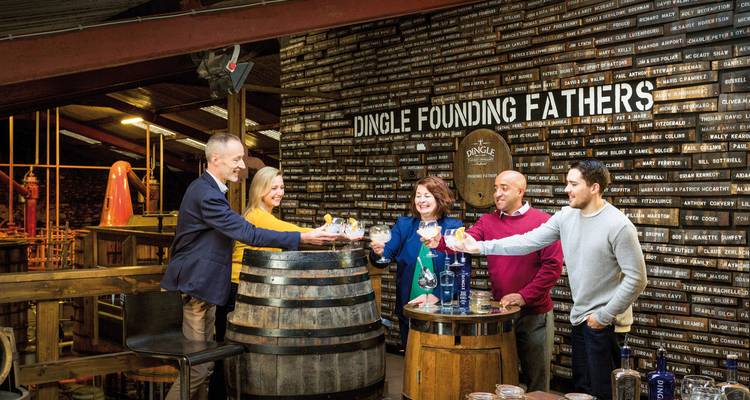 Gruppe von Menschen, die mit Gläsern in einer Brennerei anstoßen.