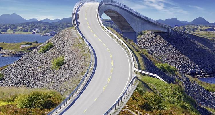 Eine erhöhte Straße auf einer Brücke zwischen felsigen Landschaften unter einem blauen Himmel.