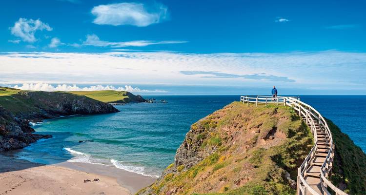Kustuitkijkpunt met een schilderachtige promenade en persoon die naar de oceaan staart.