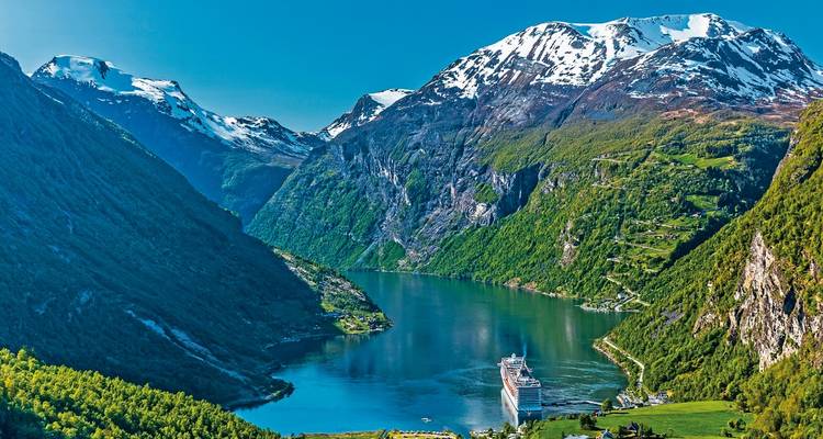 Kreuzfahrtschiff segelt in einem Fjord, umgeben von hoch aufragenden Bergen.
