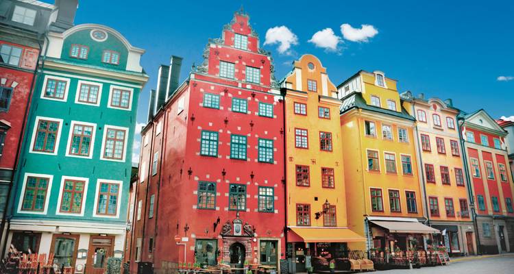 Row of brightly painted historic buildings in Stockholm’s Gamla Stan under clear sky.