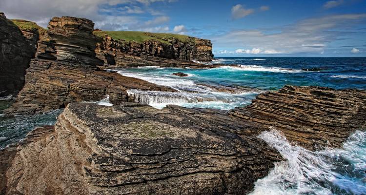 Rocky seashore with crashing waves and dramatic cliffs.