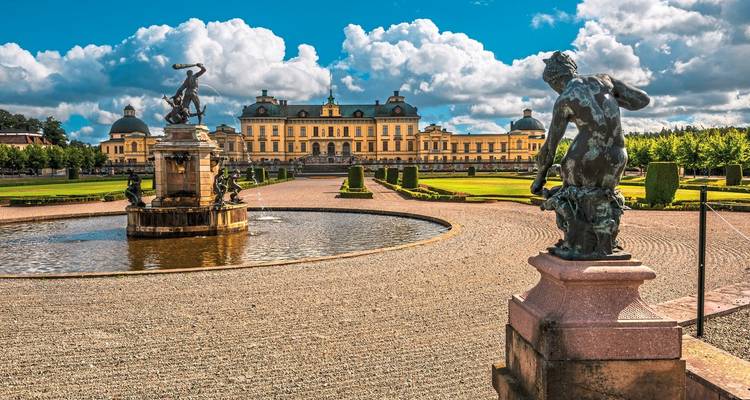 Élégant bâtiment avec des statues et une fontaine au premier plan.