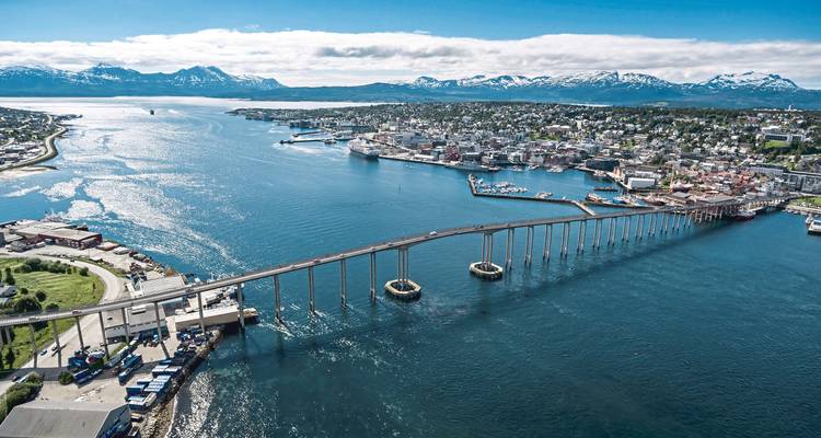 A long bridge over a bay with a distant city and mountains.