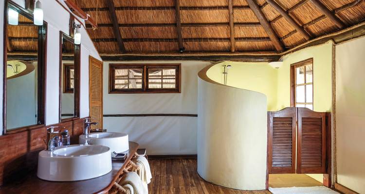 Badezimmer mit zwei Waschbecken und einer geschwungenen Duschwand.