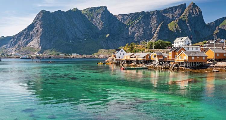 Kleurrijke paalwoningen langs de kust met bergachtergrond