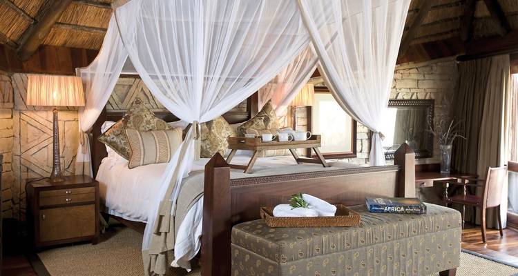 Schlafzimmer mit einem drapierten Himmelbett und gemütlicher Dekoration.