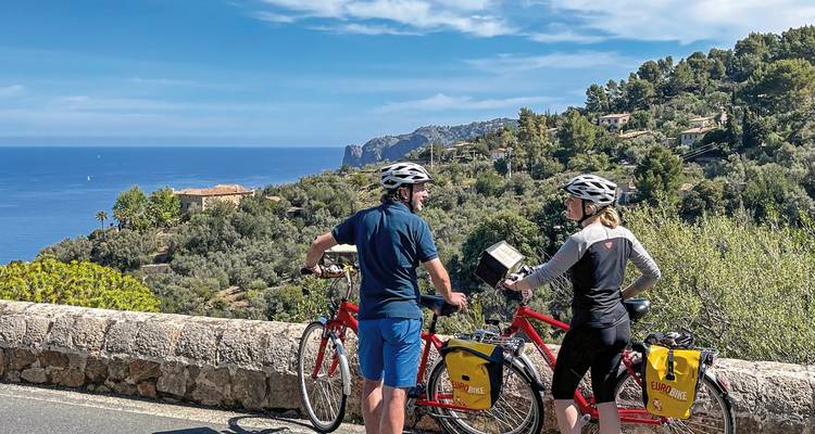 Dos ciclistas en una carretera con vista al océano.