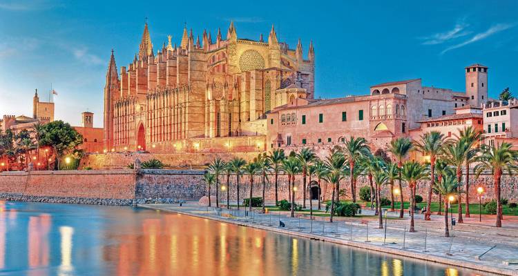 Kathedraal aan de waterkant met verlichte reflecties op het water.