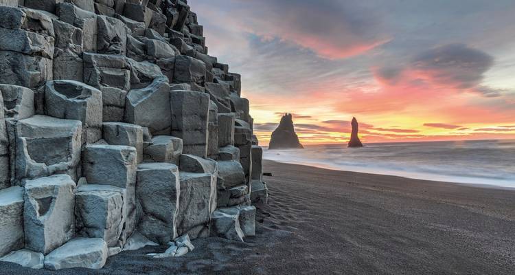 Atemberaubende Basaltsäulen am Reynisfjara-Strand unter einem farbenfrohen Himmel.