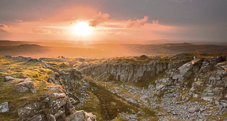 Felsige Landschaft mit einem strahlenden Sonnenuntergang über Hügeln.