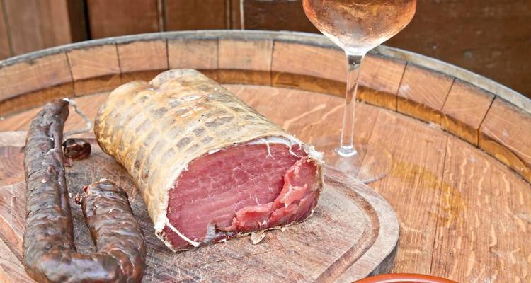 Een houten vat met charcuterie en een glas wijn.