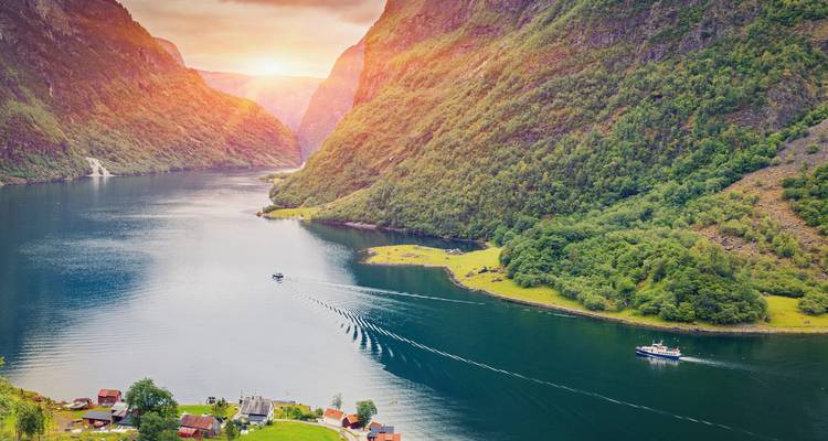 Sunset over a fjord with boats and vivid colors.