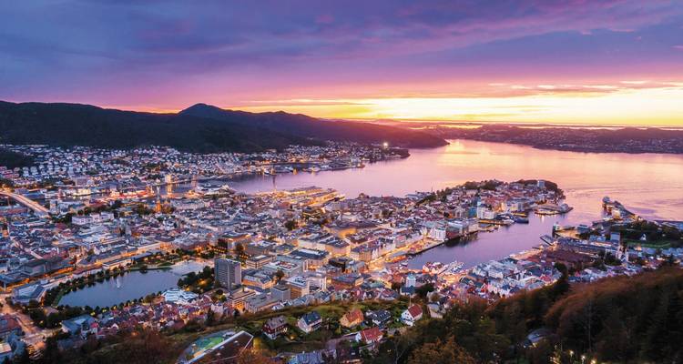 A sunset over a cityscape with a harbor and an orange sky.