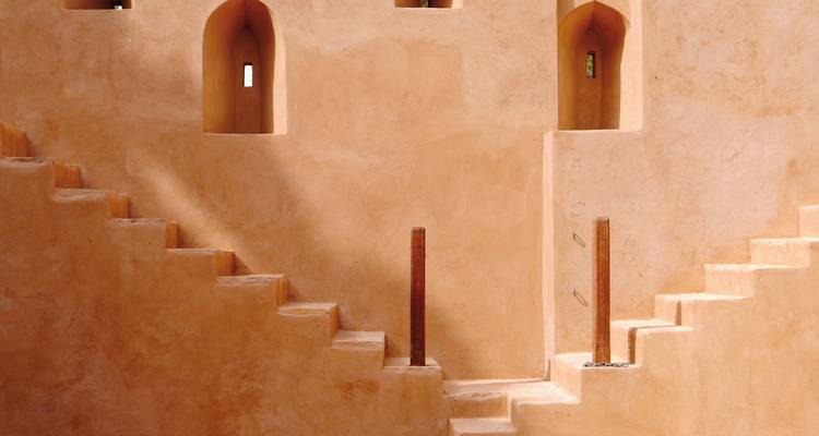 Alte Festungsmauern mit symmetrischen Treppen in warmem Licht.