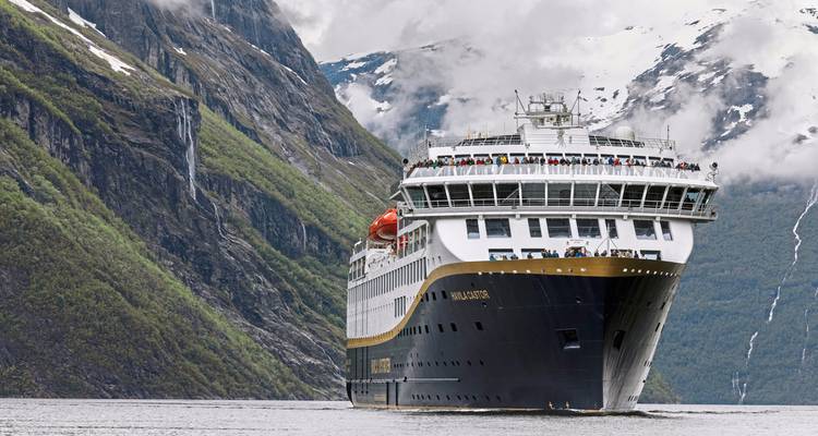 Gros plan d'un navire de croisière serein traversant un paysage de fjord montagneux.