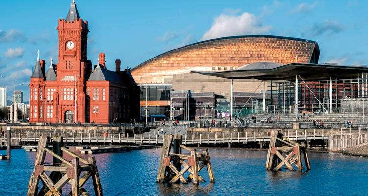 Modern cultural buildings on a waterfront with people walking.