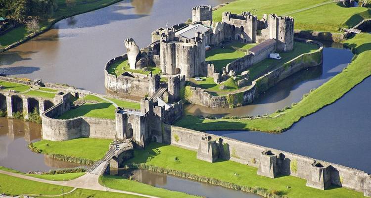 Aerial view of a large castle surrounded by a moat and green fields.