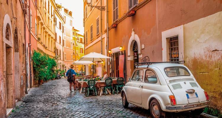 Charmante schmale Straße in Rom mit Oldtimern und Straßencafés.