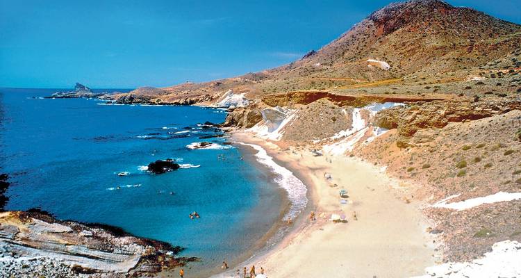 Küstenlandschaft mit einem Sandstrand und felsigem Gelände.