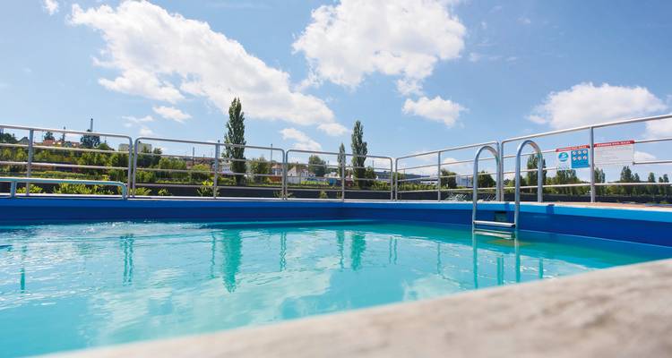 Piscine sur le pont d'un navire de croisière avec un ciel dégagé.
