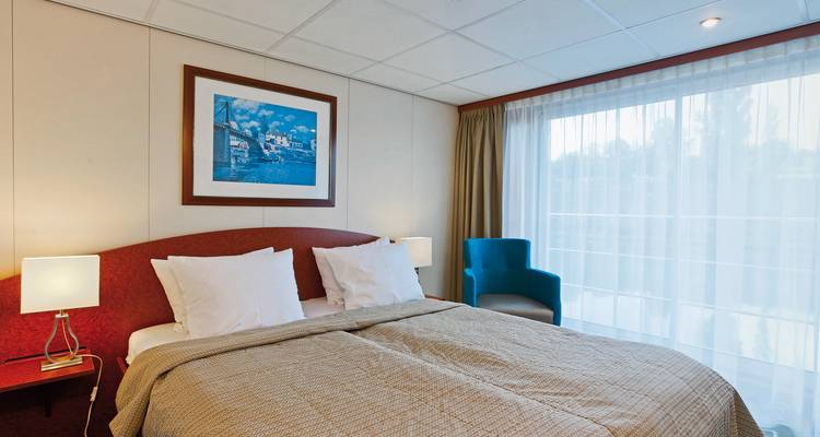 Cabine de bateau de croisière avec un lit double et une grande fenêtre.