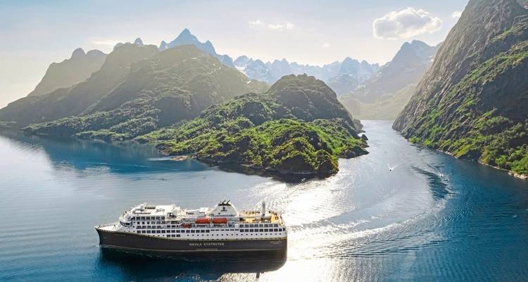 Ein Kreuzfahrtschiff fährt durch einen atemberaubenden Fjord, umgeben von hohen Bergen.