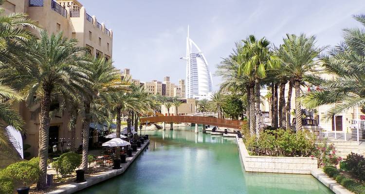 Kanal gesäumt von Palmen und dem Burj Al Arab im Hintergrund.