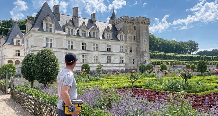 Cyclist admiring a large stone mansion with manicured gardens.