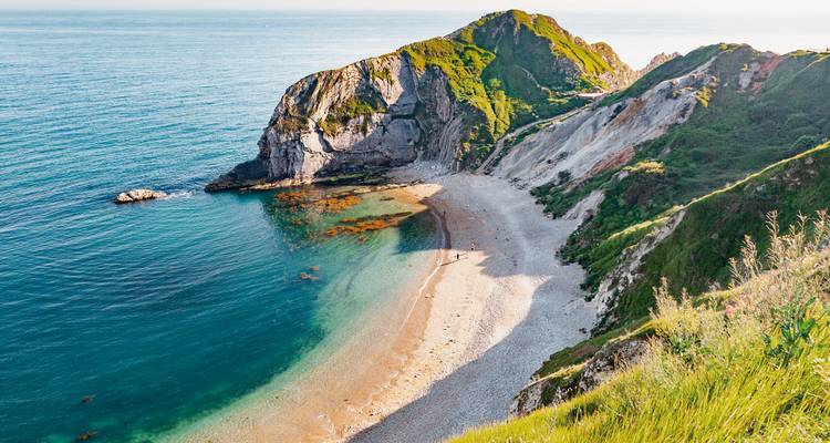 Ein friedlicher Sandstrand mit Klippen am Meer.